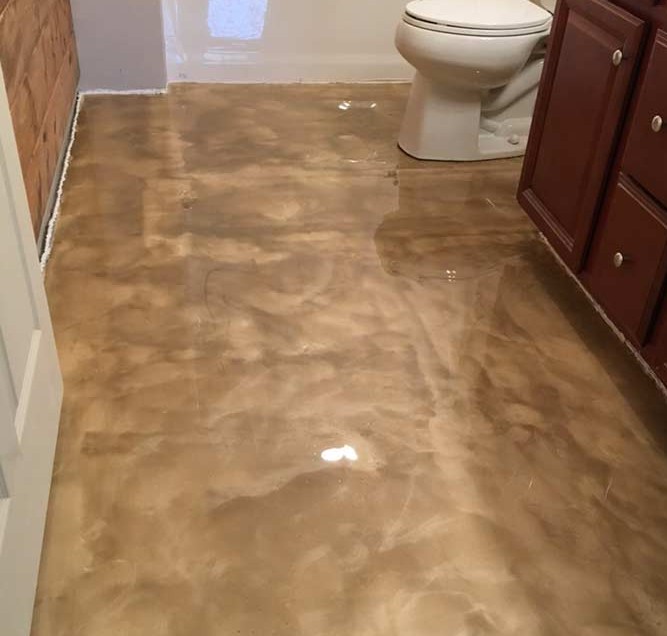 Metallic epoxy floor installed in Myrtle Beach bathroom — warm tan caramel finish by Bakerss Property Maintenance